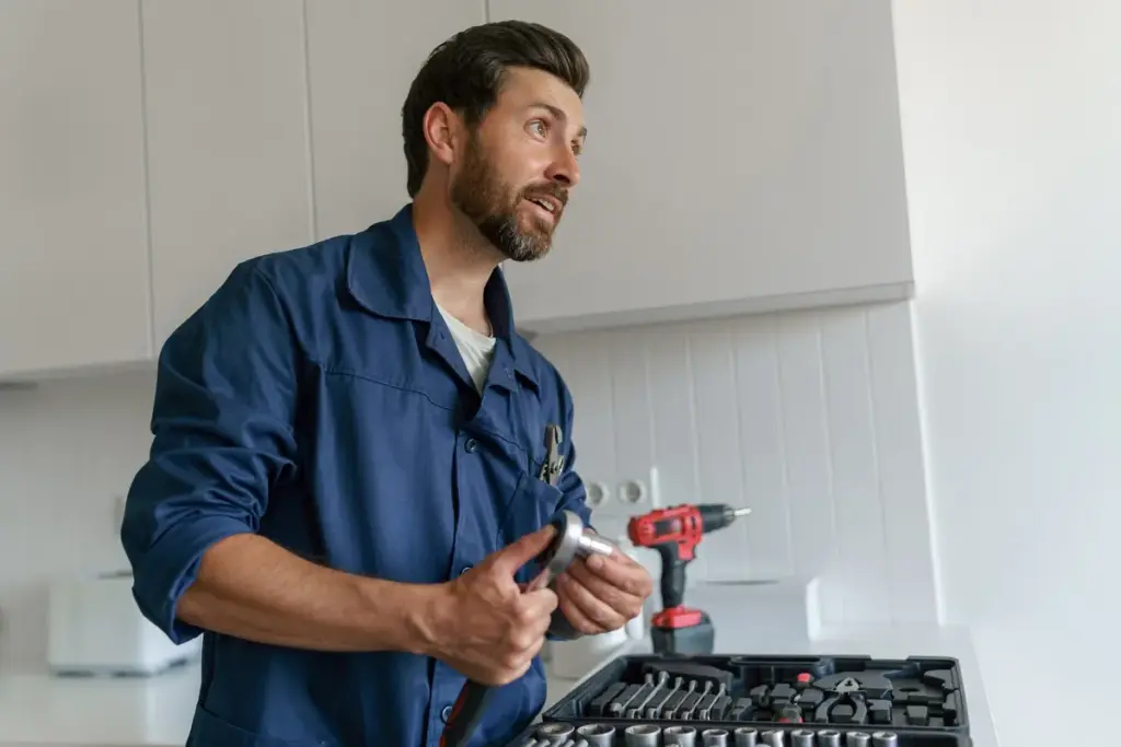 A professional handyman with a tool bag stands in a kitchen, ready to assist with appliance repairs.