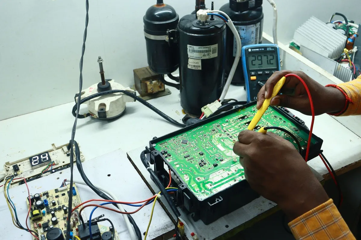 A technician repairs an air conditioning PCB using various tools, highlighting affordable appliance repair solutions.