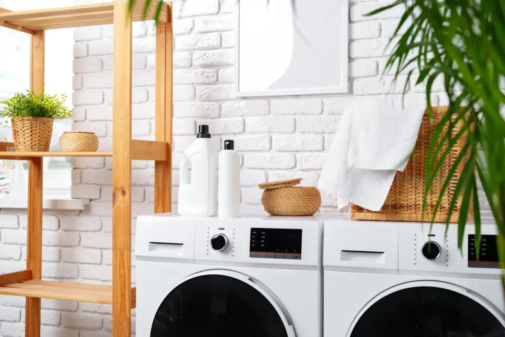 A modern laundry room featuring white appliances and green plants, emphasizing a clean and organized space.